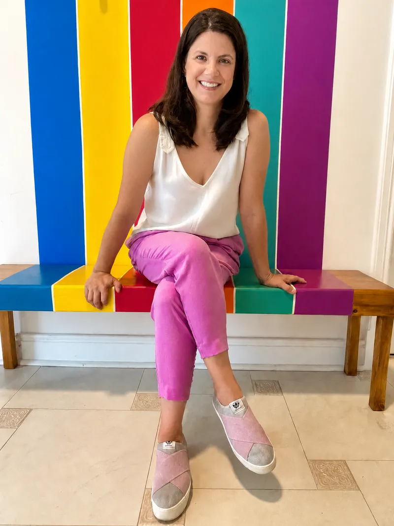 Telma Luperi sentada no banco colorido da Lumicá, sorrindo.
